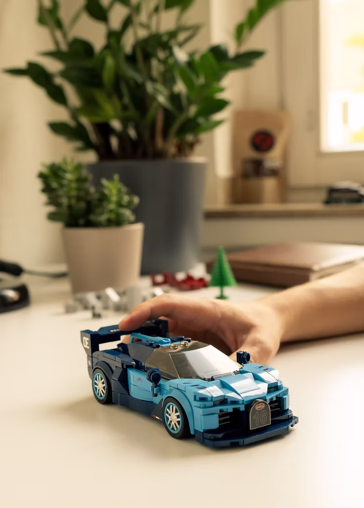 Hand placing a brick-built sports car on a desk